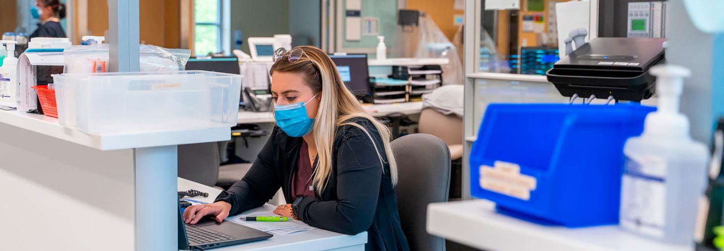 nurse with mask sitting at work desk